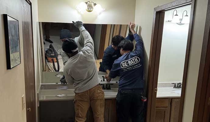 Great Lakes Home Renovations professionals installing a large mirror above a bathroom vanity