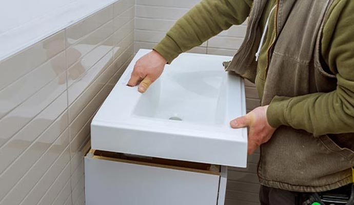 Person installing a bathroom sink on vanity cabinet