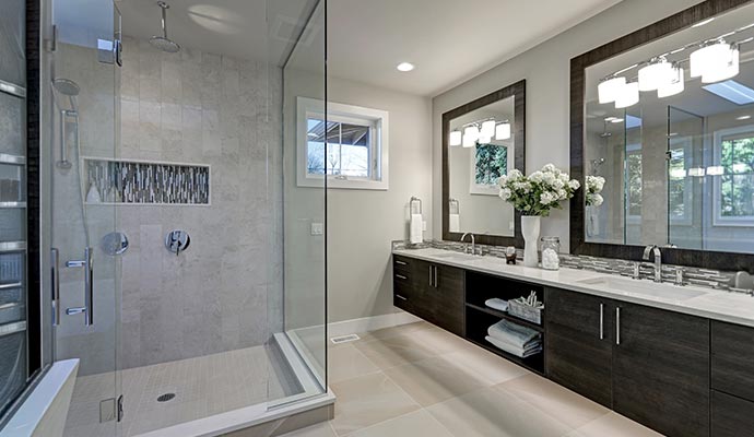 Bathroom with glass shower enclosure tiled walls double vanity and large framed mirrors