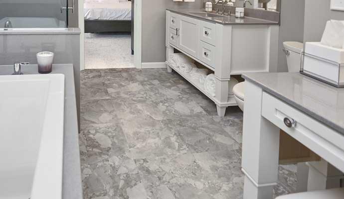 Gray tile bathroom floor with white vanity bathtub