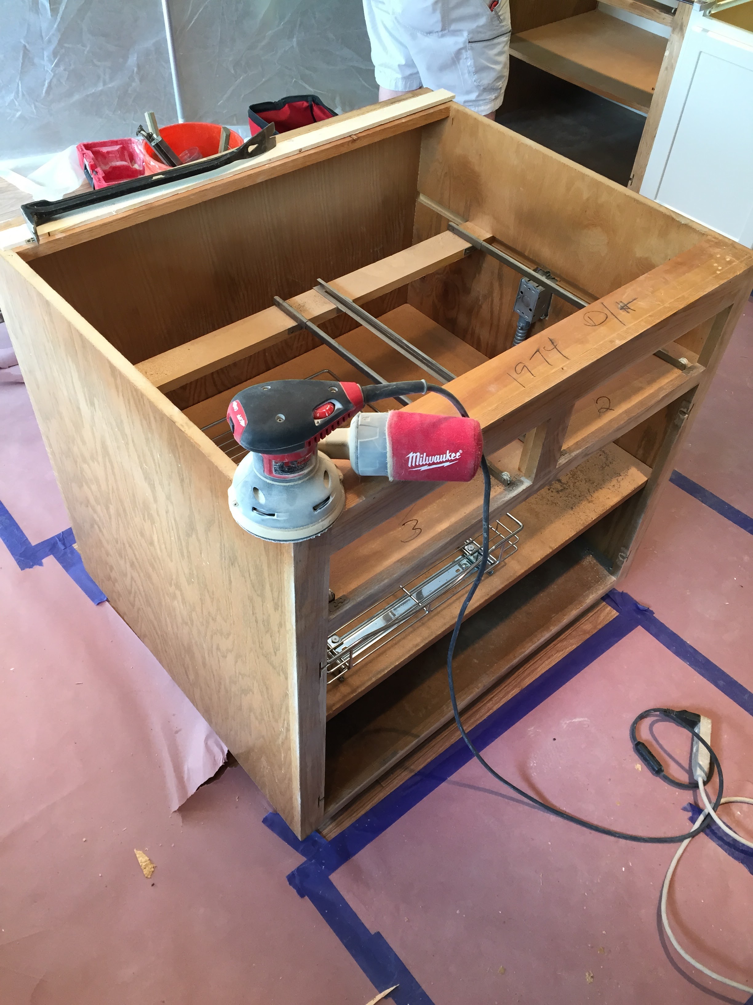 DURING - An orbital sander is used to get old paint and stain off and ready for cabinet boxes to be resurfaced