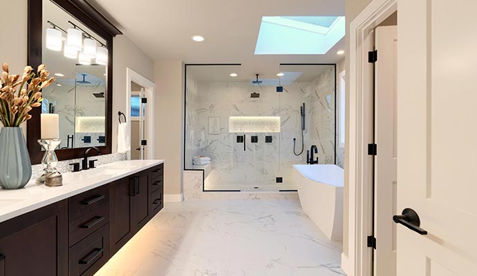 Spacious bathroom with double vanity, glass walk-in shower, skylight, and freestanding tub