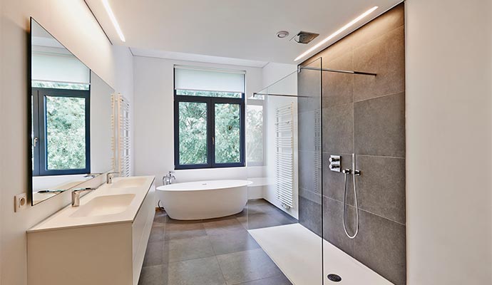 bathroom with glass walk-in shower, freestanding tub, and large window