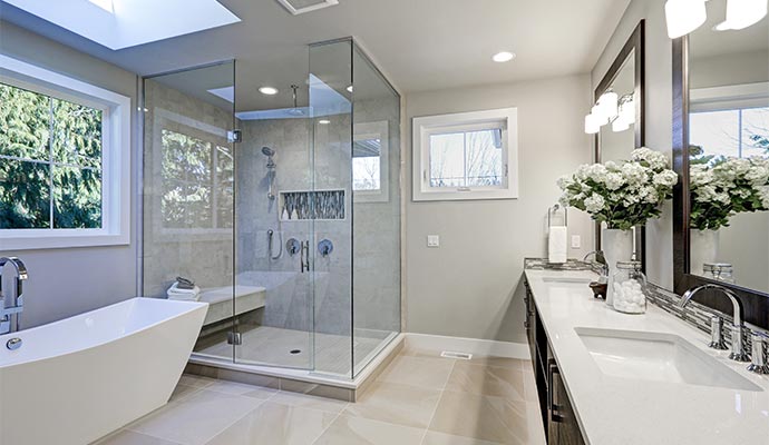 Modern bathroom with glass shower enclosure freestanding bathtub double vanity and large windows