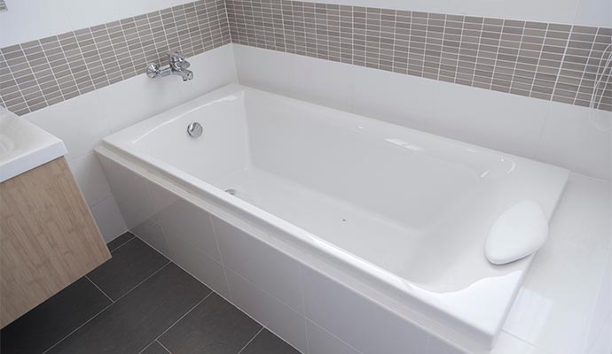 White bathtub with wall-mounted faucet and tiled surround